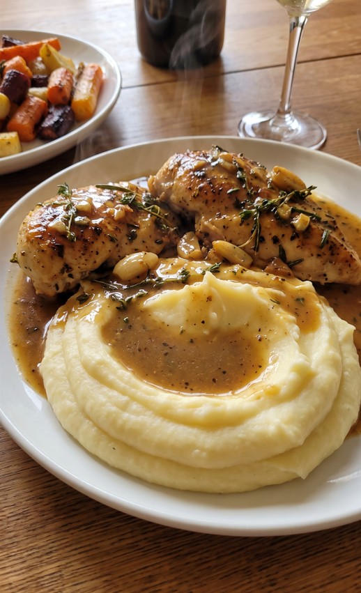 Golden herb butter chicken served with mashed potatoes and creamy gravy