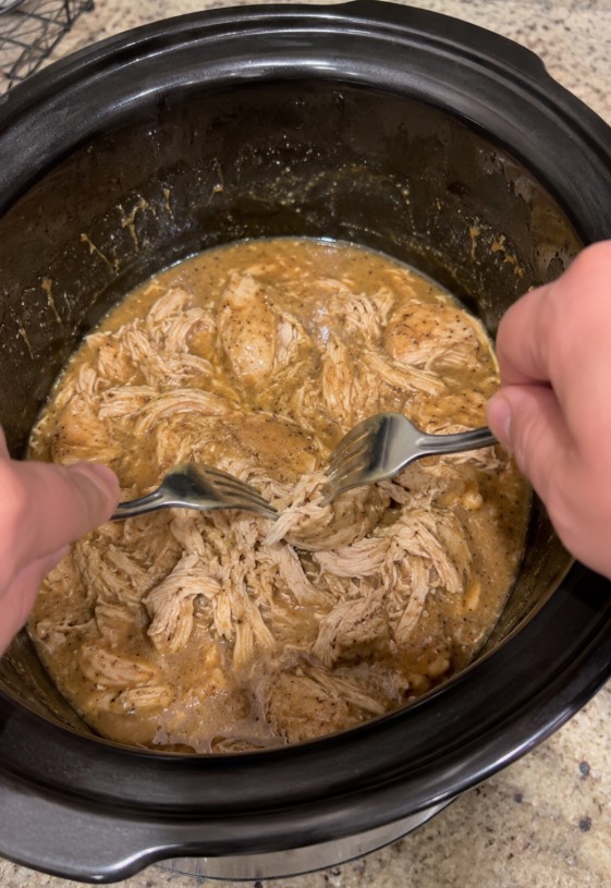 Browned chicken breasts covered with homemade gravy in a slow cooker