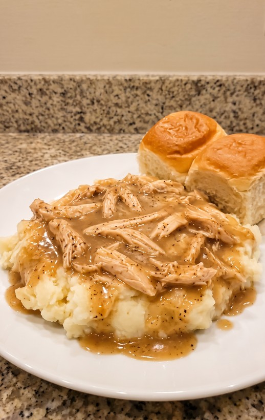 Slow cooker chicken and gravy served over creamy mashed potatoes